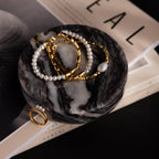 Gold and pearl jewelry elegantly displayed on an Onyx Marble Jewelry Dish, set atop magazines with neutral-toned covers.