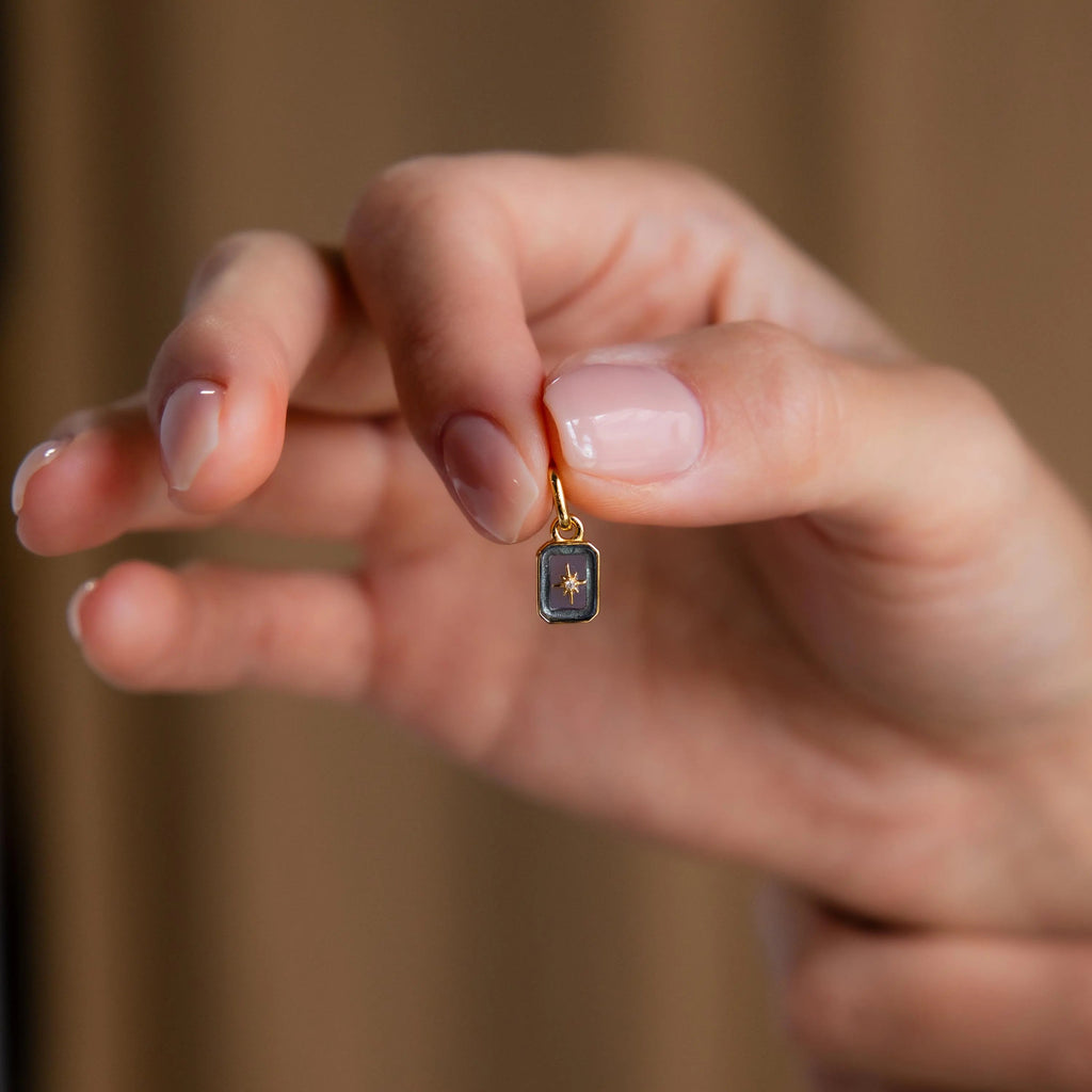 Hand holding a Gold North Star Birthstone Charm in Aquamarine.