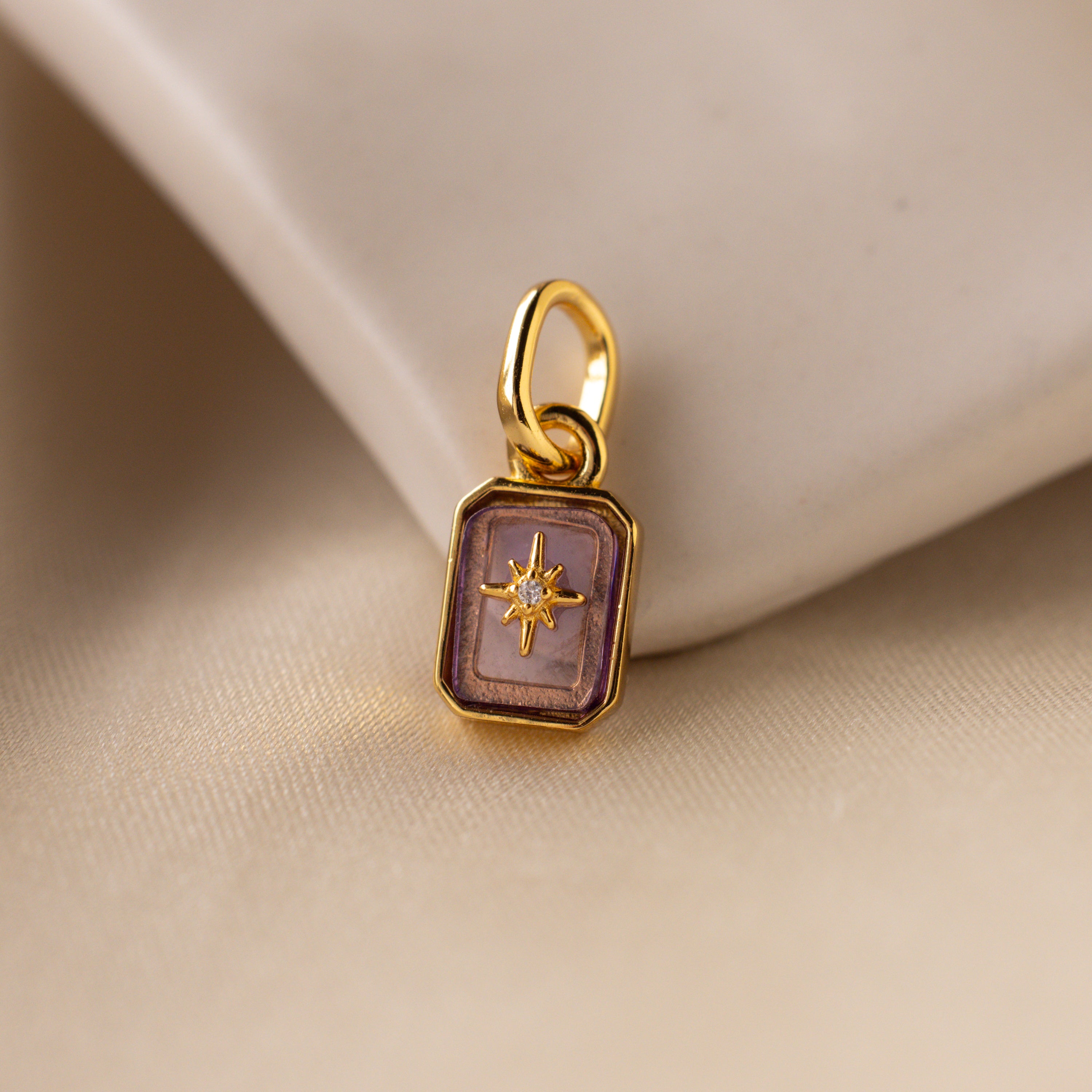 Up close of a light purple alexandrite north star charm with a pavé CZ diamond in the center.