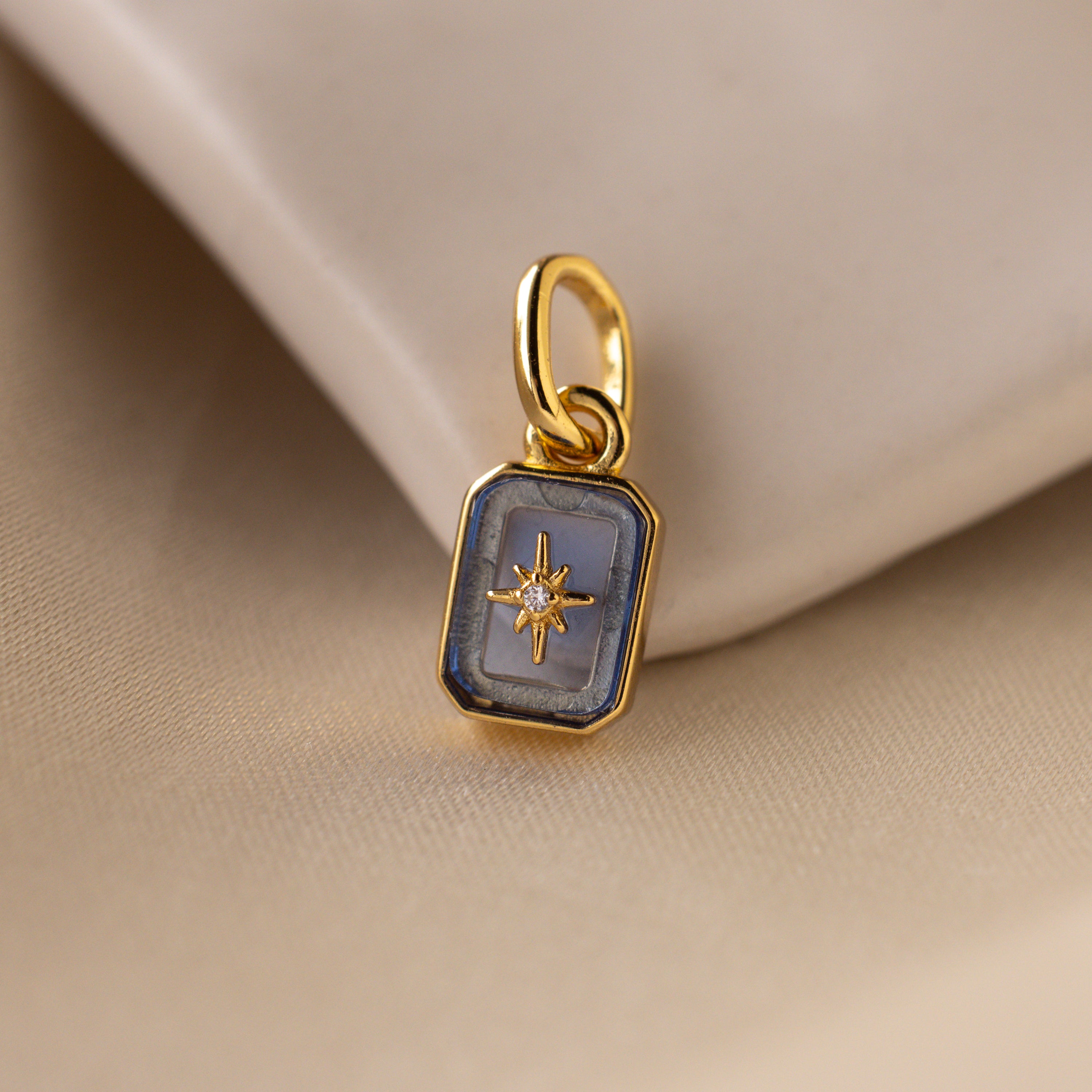 Up close of a blue aquamarine north star charm with a delicate pavé diamond in the center.