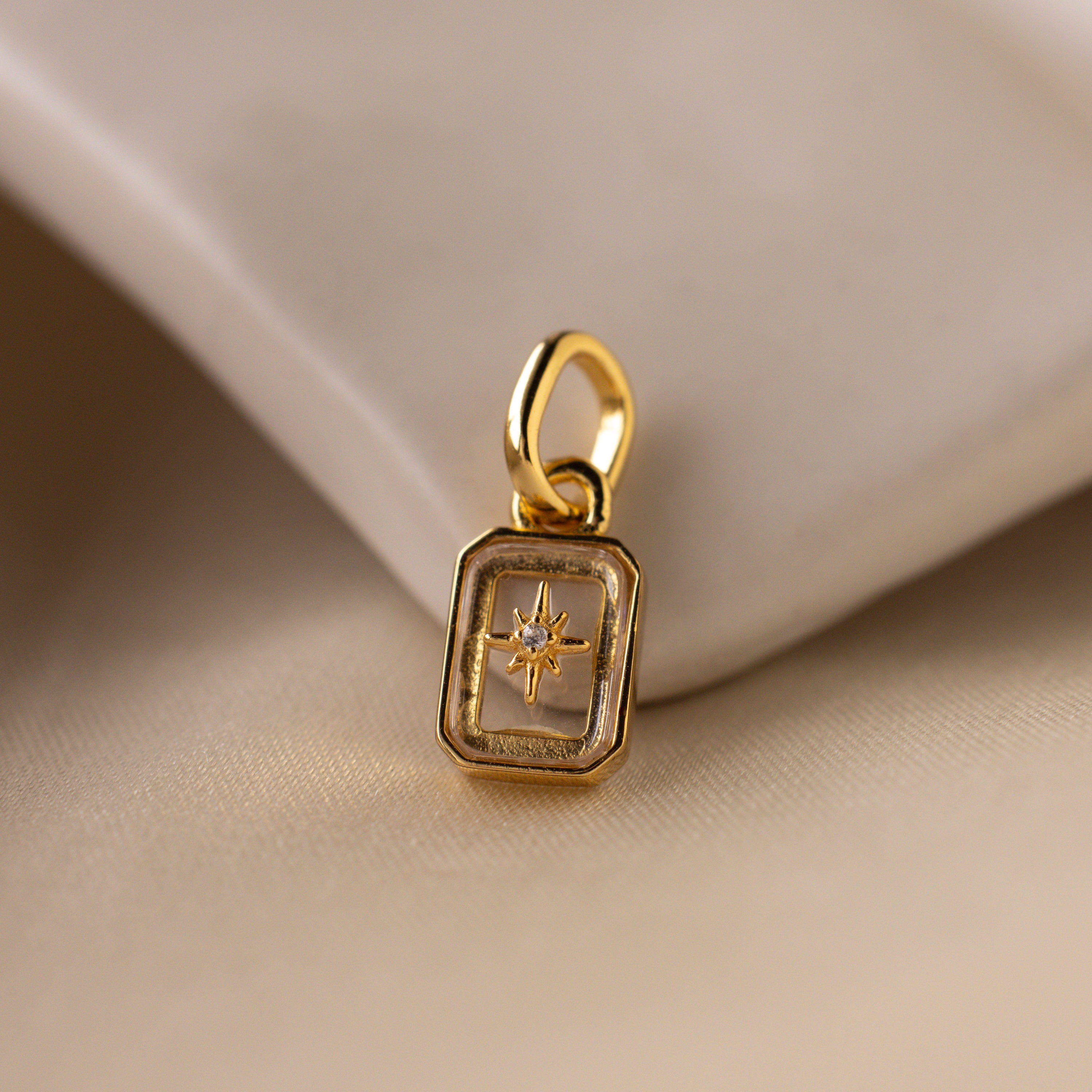 Up close of a clear diamond north star charm with a delicate pavé diamond in the center.