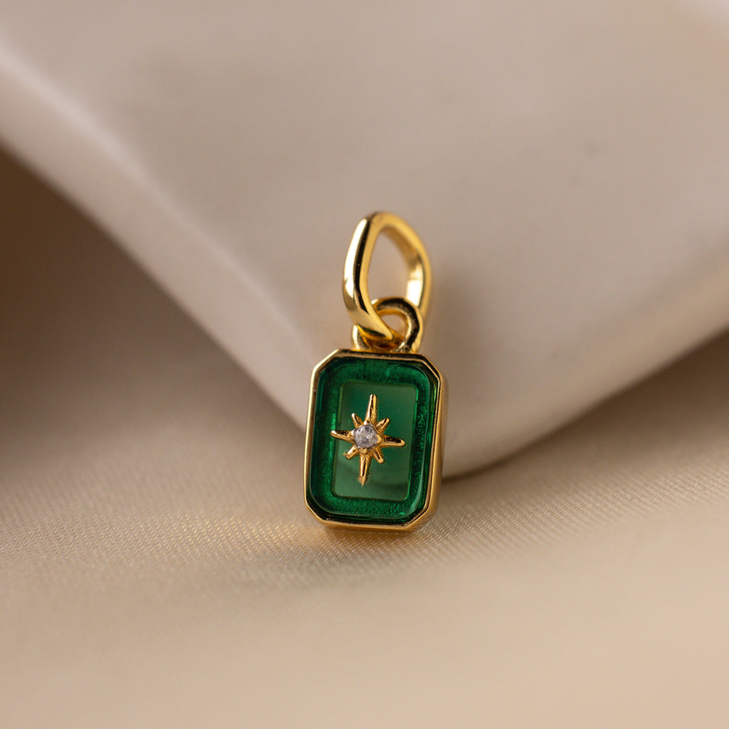 Up close of a green emerald north star charm with a delicate pavé diamond in the center.