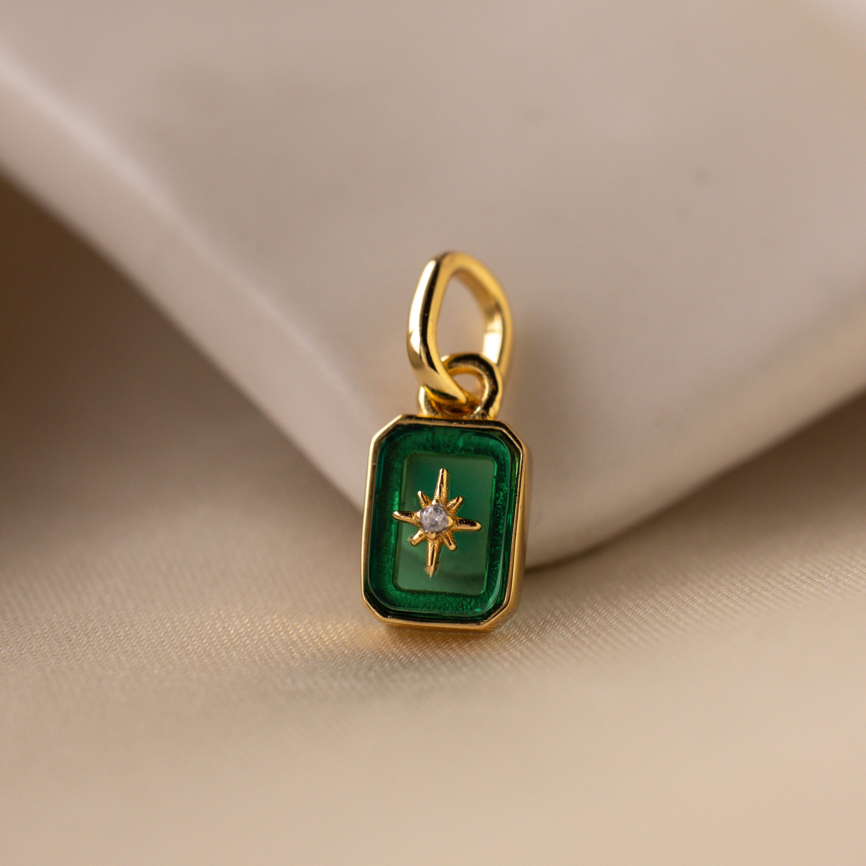 Up close of a green emerald north star charm with a delicate pavé diamond in the center.