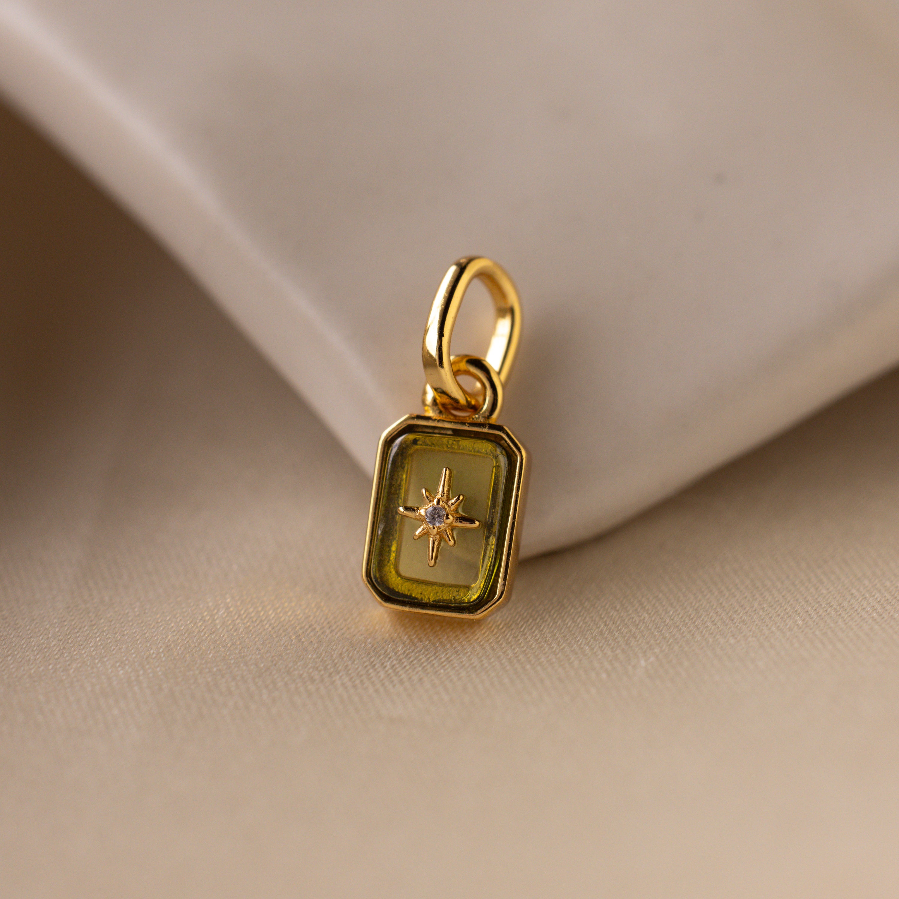 Up close of a green peridot north star charm with a delicate pavé diamond in the center.