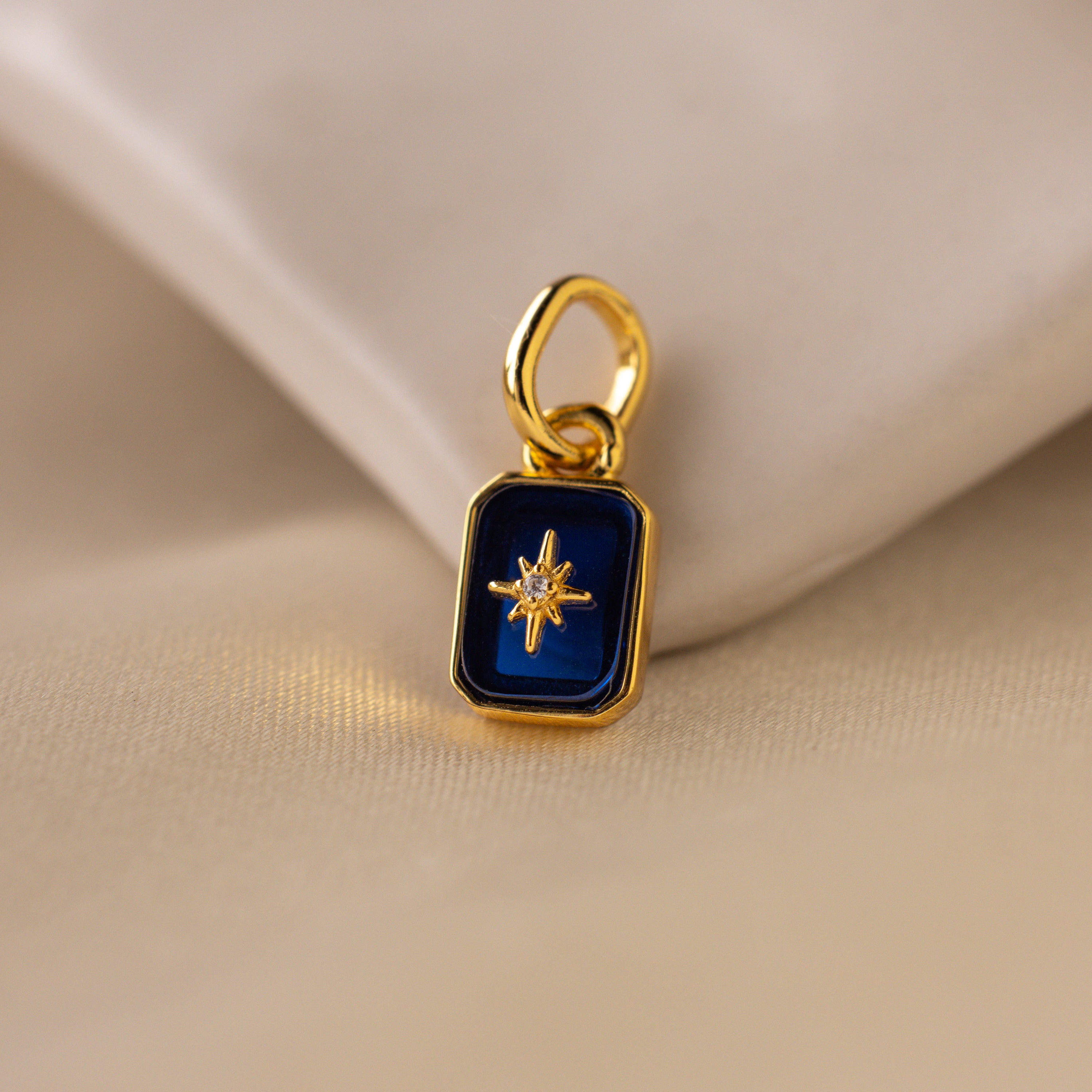 Up close of a deep blue sapphire north star charm with a delicate pavé diamond in the center.