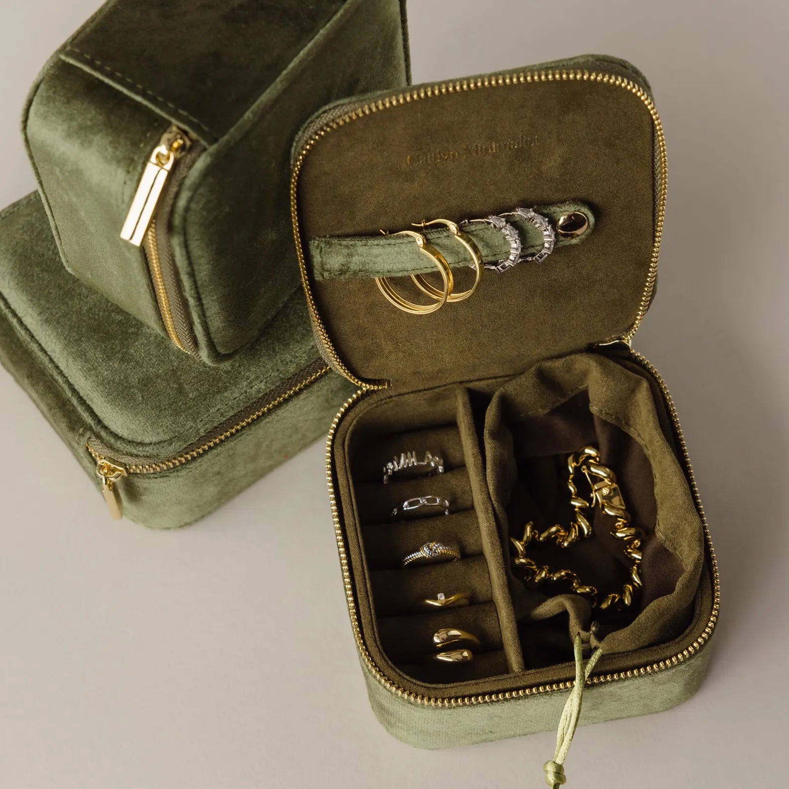 The Green Velvet Jewelry Box opens to display rings and bracelets, while a closed case sits behind—an elegant travel companion perfect for stylish jewelry storage on the go.