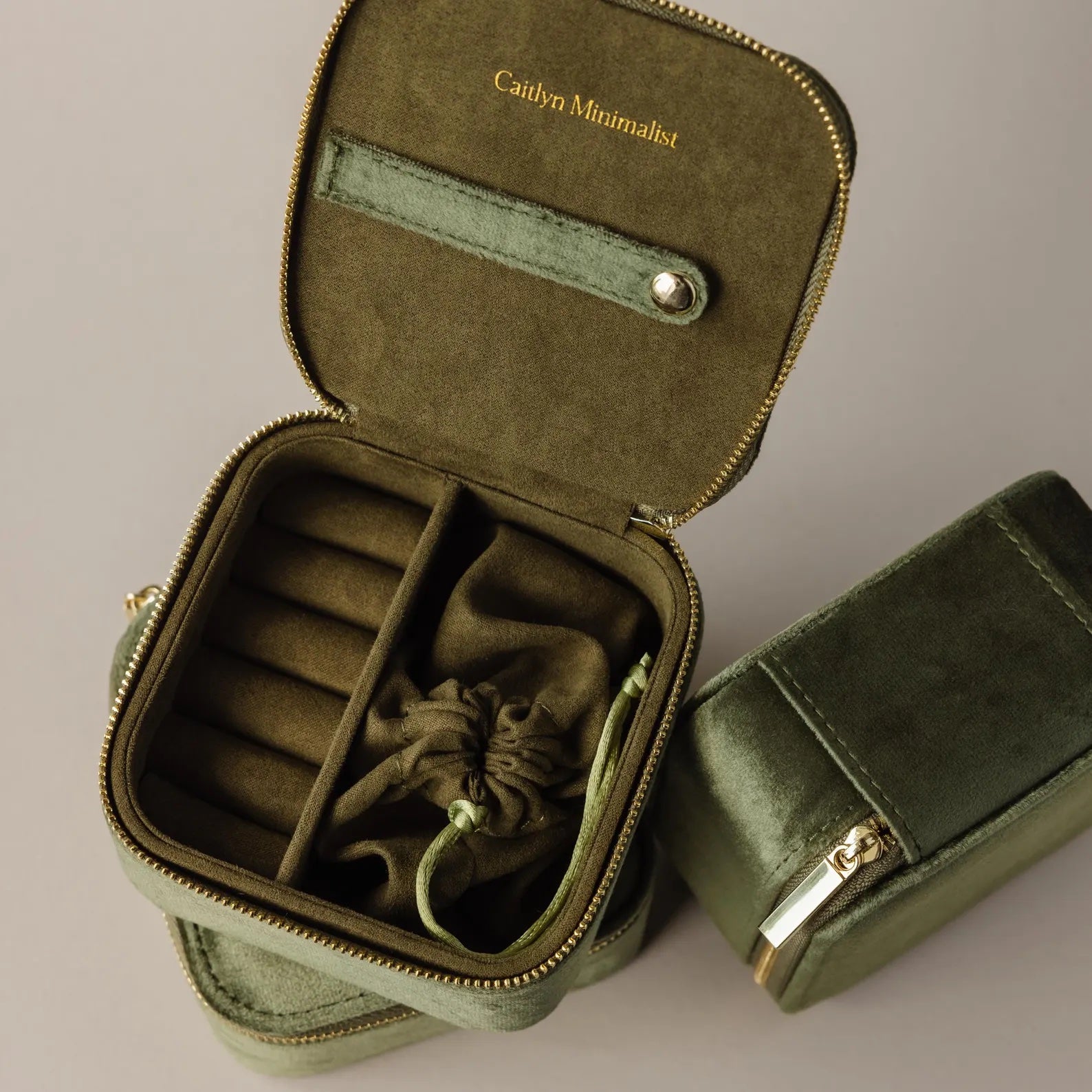 The Green Velvet Jewelry Box features compartments and a drawstring pouch, ideal for jewelry storage or travel. The lid is adorned with "Caitlyn Minimalist" in gold text.