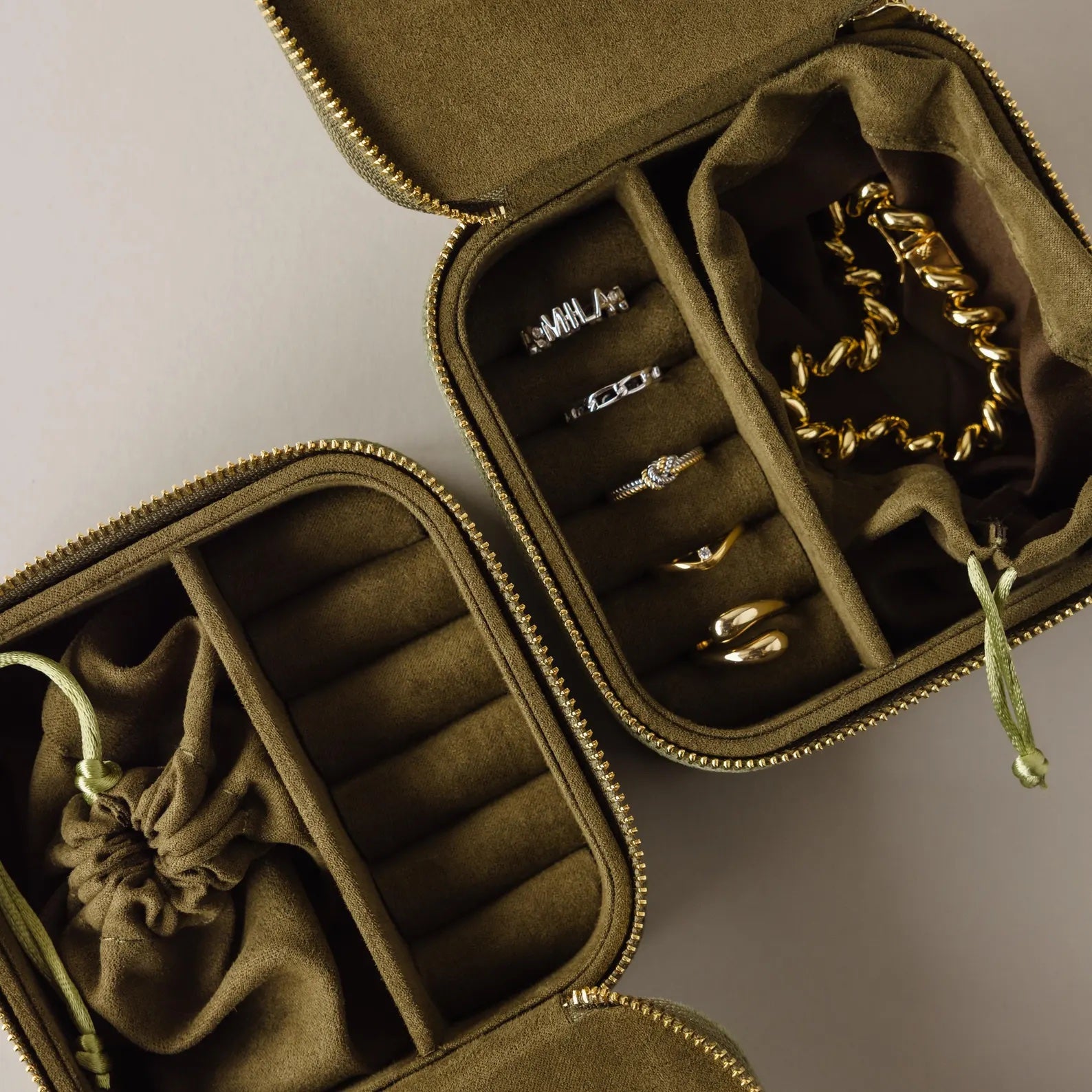 Two Green Velvet Jewelry Boxes, perfect for travel, open to display assorted gold and silver rings and bracelets.