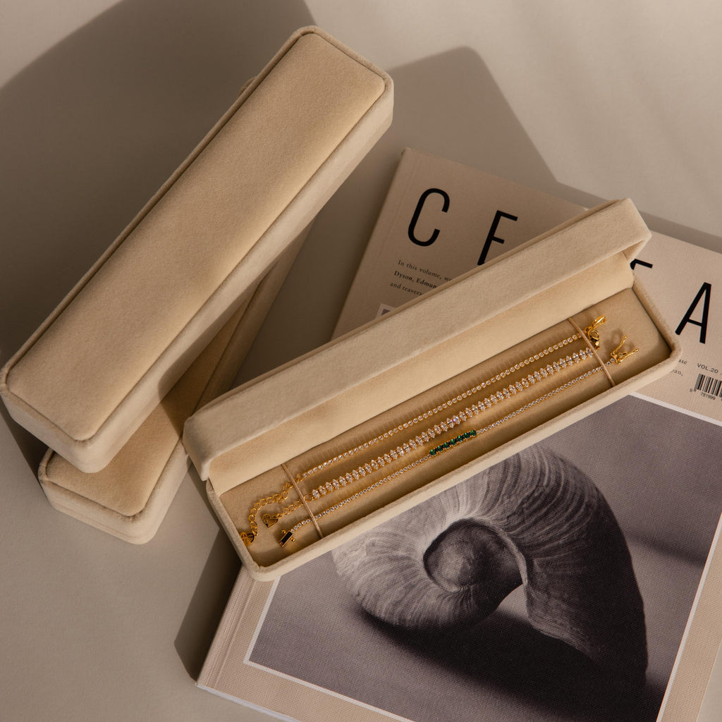 A Bracelet Travel Case holds a gold bracelet and rests on a magazine with a black-and-white shell photo on its cover.