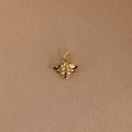The Honeybee Charm in 18K Gold, adorned with small gemstones, is shown against a plain light brown background.