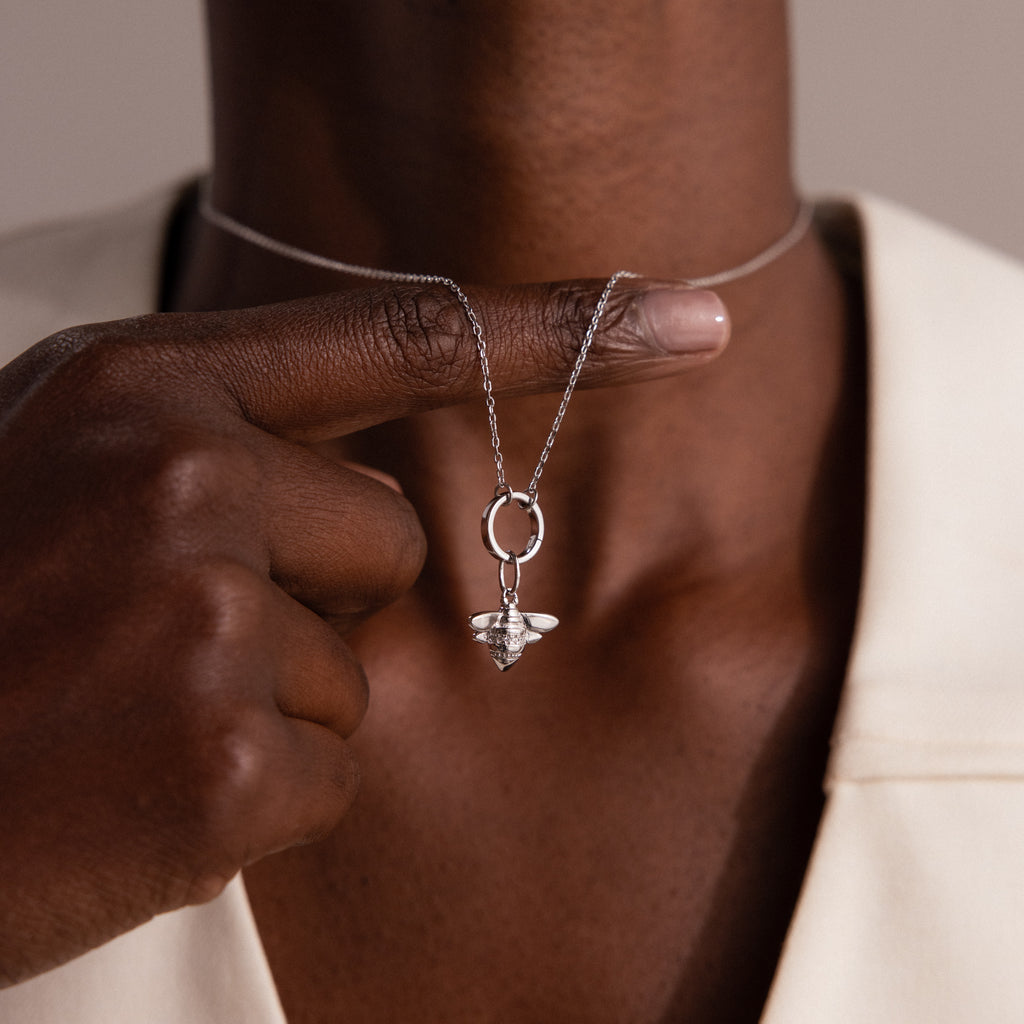 A person holds a silver necklace with the Honeybee Charm pendant near their neck, highlighting elegant nature-inspired jewelry.
