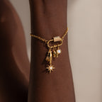 A gold charm bracelet with star, hand, pearl, and letter N charms is secured by the Opal Carabiner Clasp in 18K Gold for a unique opal jewelry accent on your wrist.