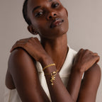 Woman in a white sleeveless top poses with arms crossed, wearing a gold bracelet featuring the Opal Carabiner Clasp in 18K Gold and dangling charms.