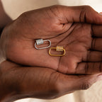 Two hands hold gold and silver gemstone-studded oval links side by side—ideal as the Opal Carabiner Clasp or a charm connector for your opal jewelry.