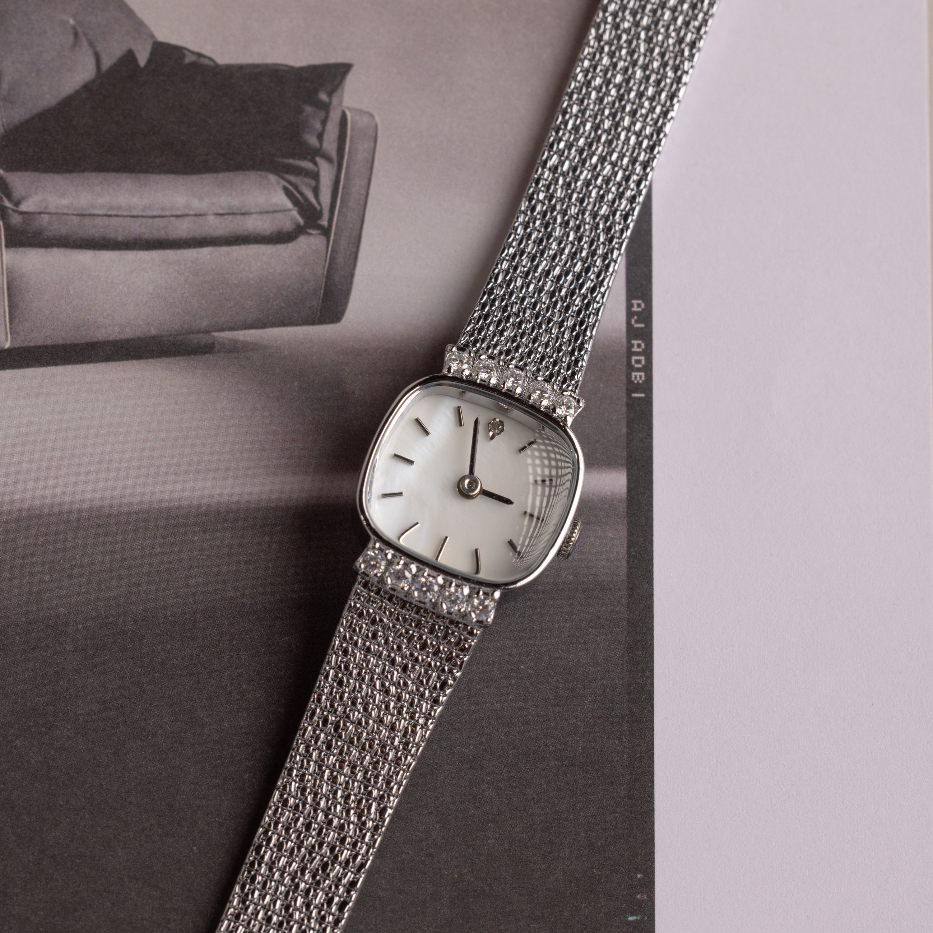 Close up of our Luxe Square Timepiece watch in Sterling Silver, laid on a black and white photo