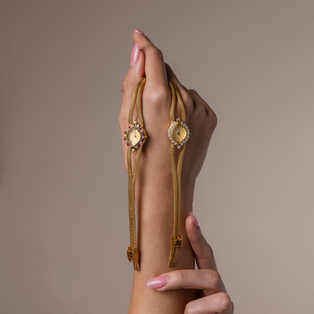 A model's hand holding both of our Duo Chain Gemstone Timepiece watch in diamond and ruby.