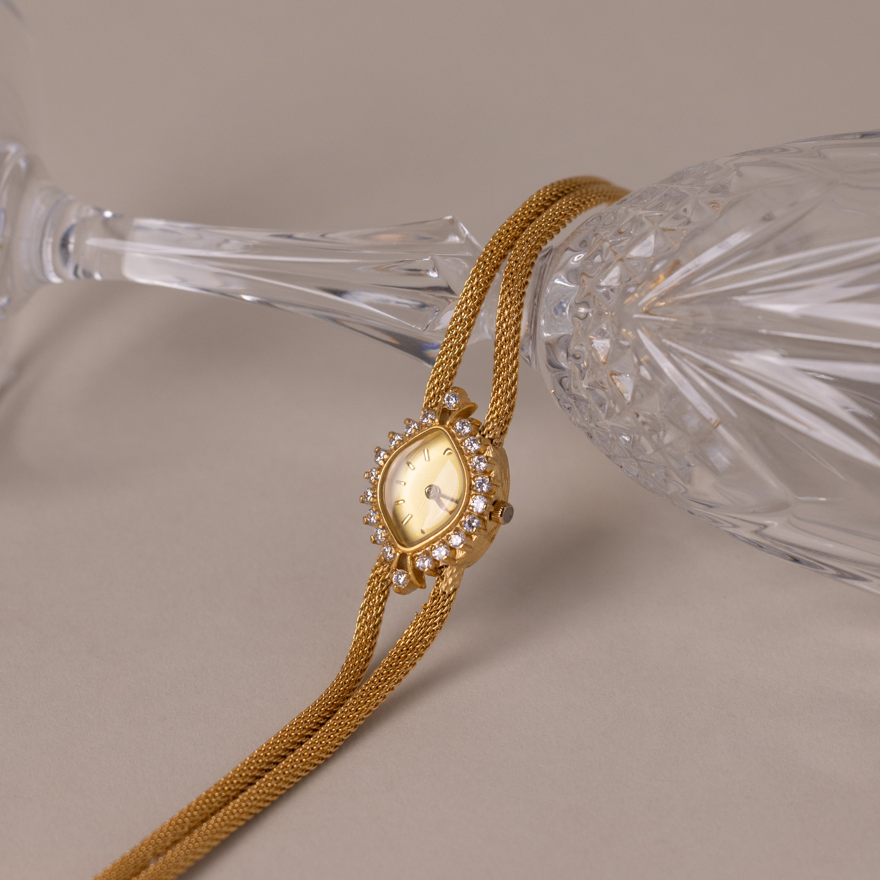 Close up of our Duo Chain Diamond Timepiece watch against a clear glass cup