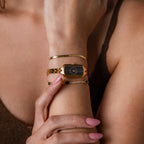 Close up of a model's wrist wearing our Midnight Link Timepiece watch, styled with our Herringbone Bracelet and Birthstone Tennis Bracelet