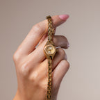 A model's hand holding our Petite Round Timepiece watch 