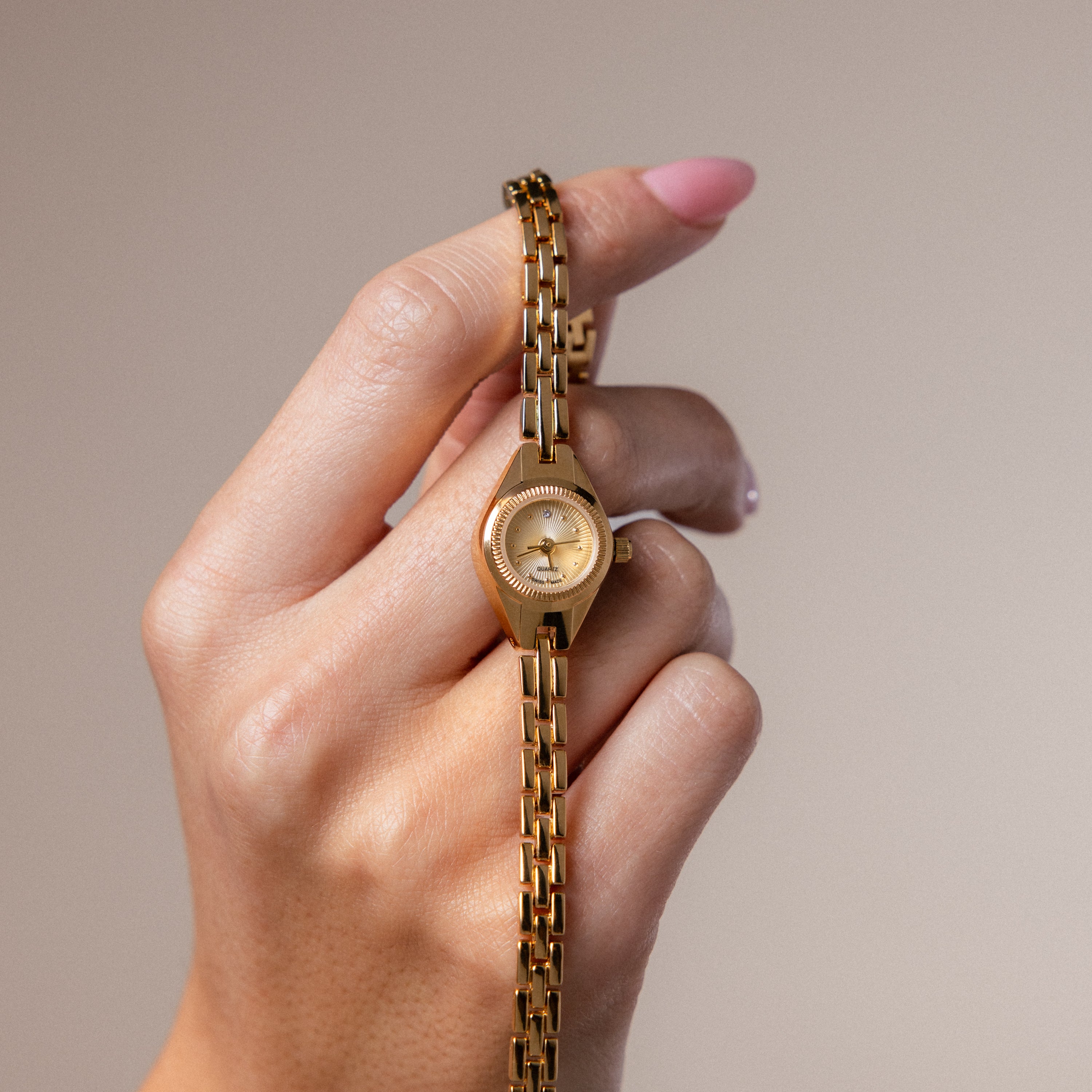 A model's hand holding our Petite Round Timepiece watch 