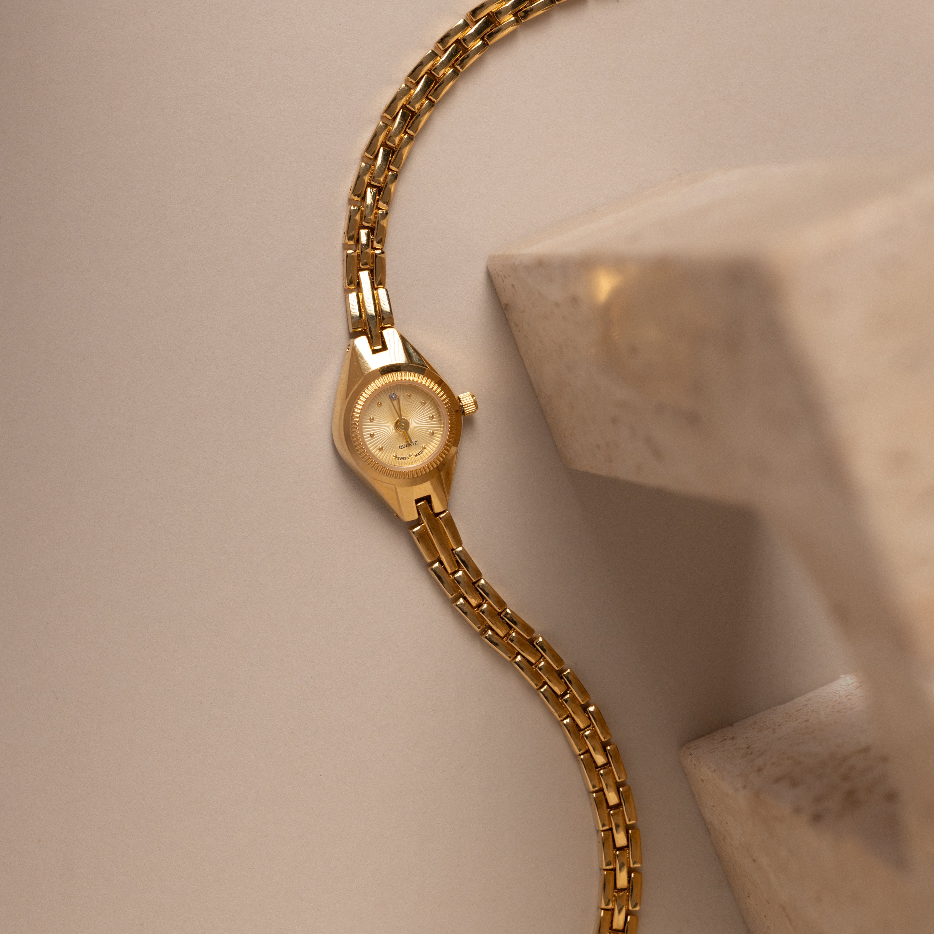 Our Petite Round Timepiece watch on a beige background