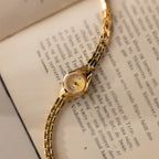 Close up of our Petite Round Timepiece watch laid on top of a book page