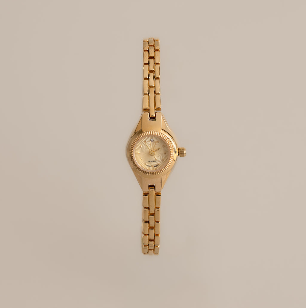 Our Petite Round Timepiece watch on a beige background