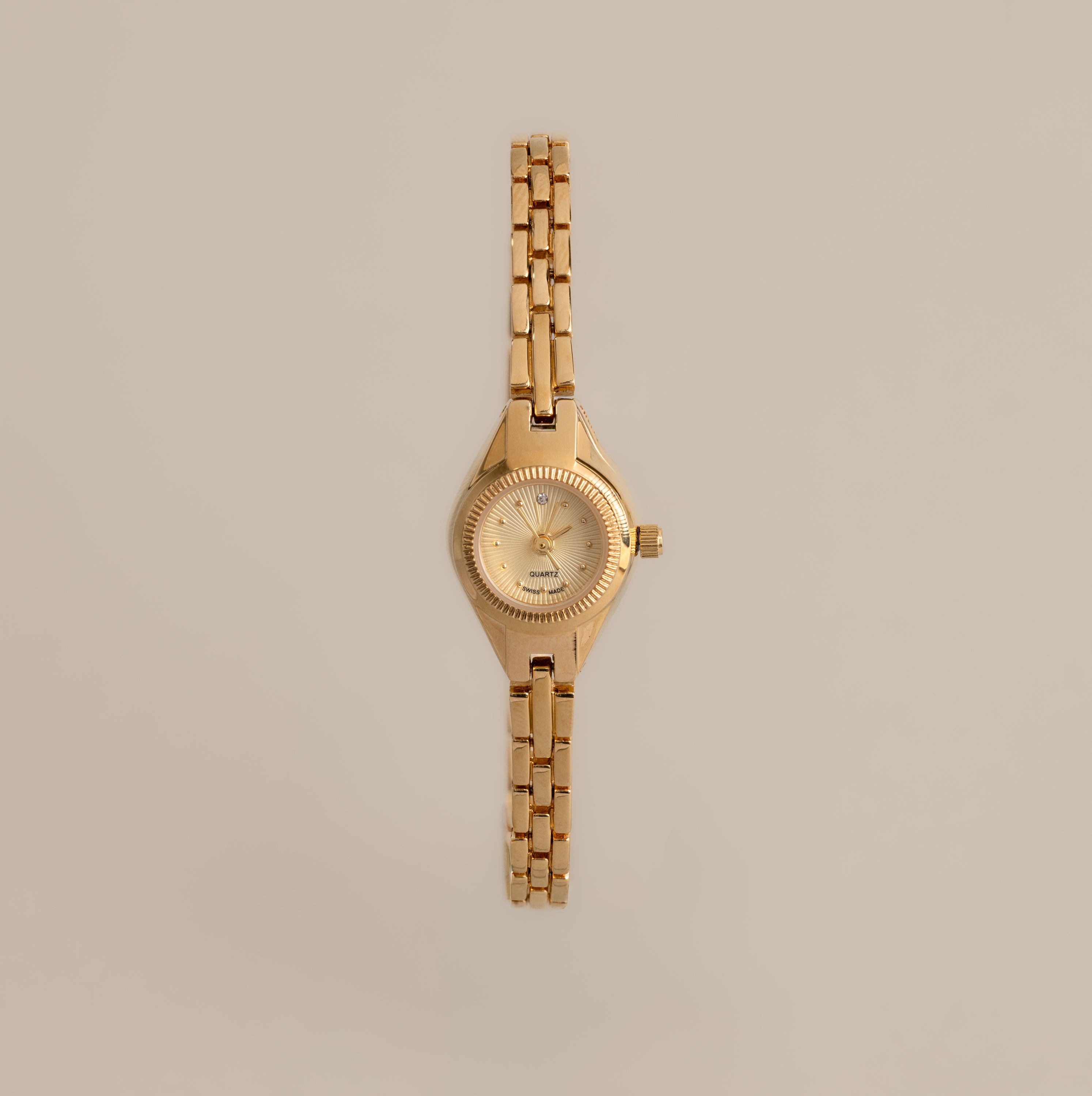 Our Petite Round Timepiece watch on a beige background