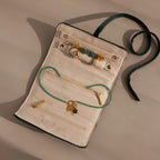 The Velvet Roll-Up Jewelry Case is shown on a beige background with gold earrings, a green beaded necklace, and gold charms.