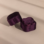 Two Purple Flower Velvet Ring Boxes sit in soft lighting on a beige surface.
