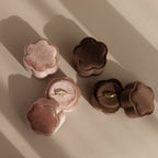 Two Flower Velvet Ring Boxes, one pink and one brown, each display a gold ring on a beige surface—making this set the ideal proposal accessory.