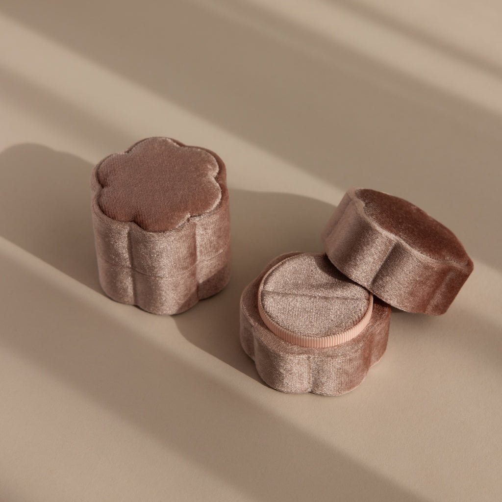 Two Flower Velvet Ring Boxes in pink velvet, shaped like flowers, rest on a beige surface and cast soft shadows.