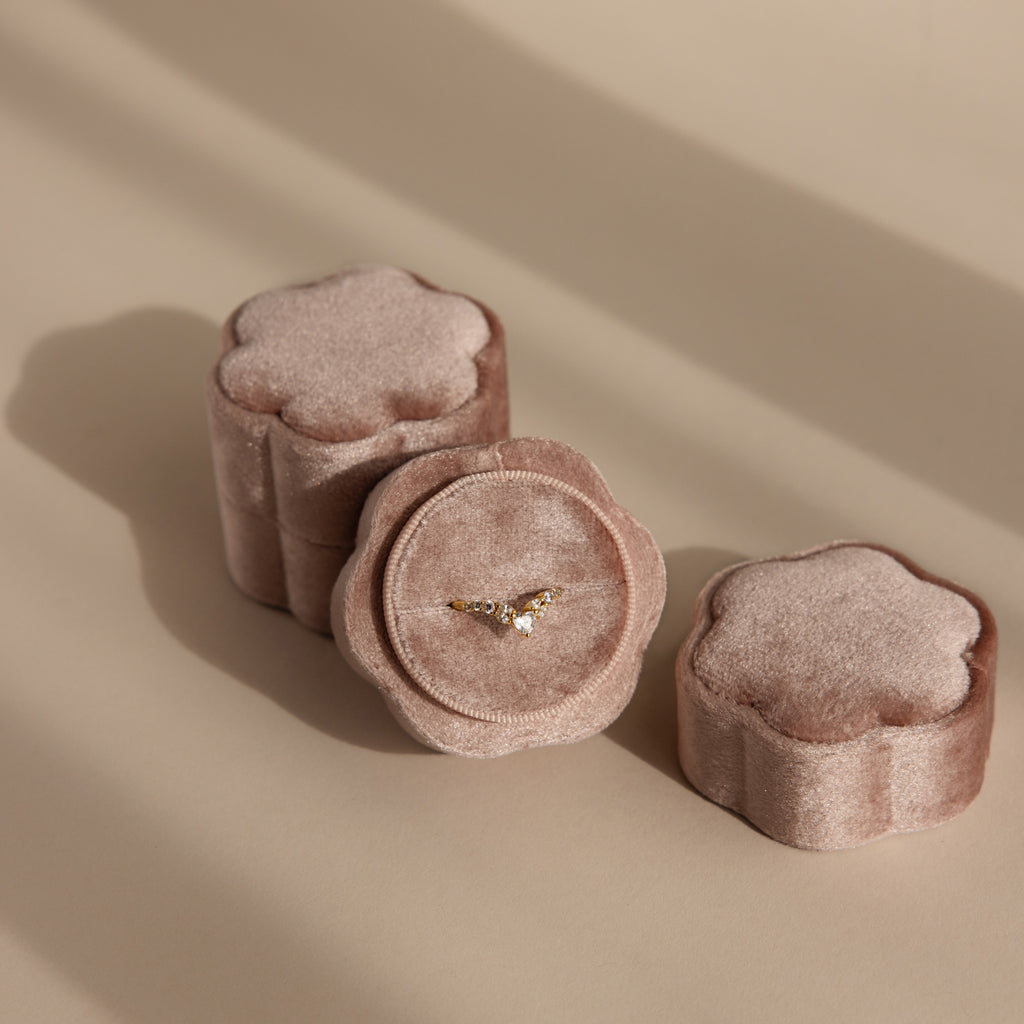 A gold ring in a Pink Flower Velvet Ring Box, with two closed matching boxes next to it.