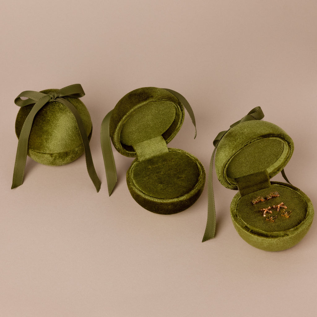 Three Green Velvet Round Ring Boxes—two open, one closed with ribbons; one box displays a pair of earrings.