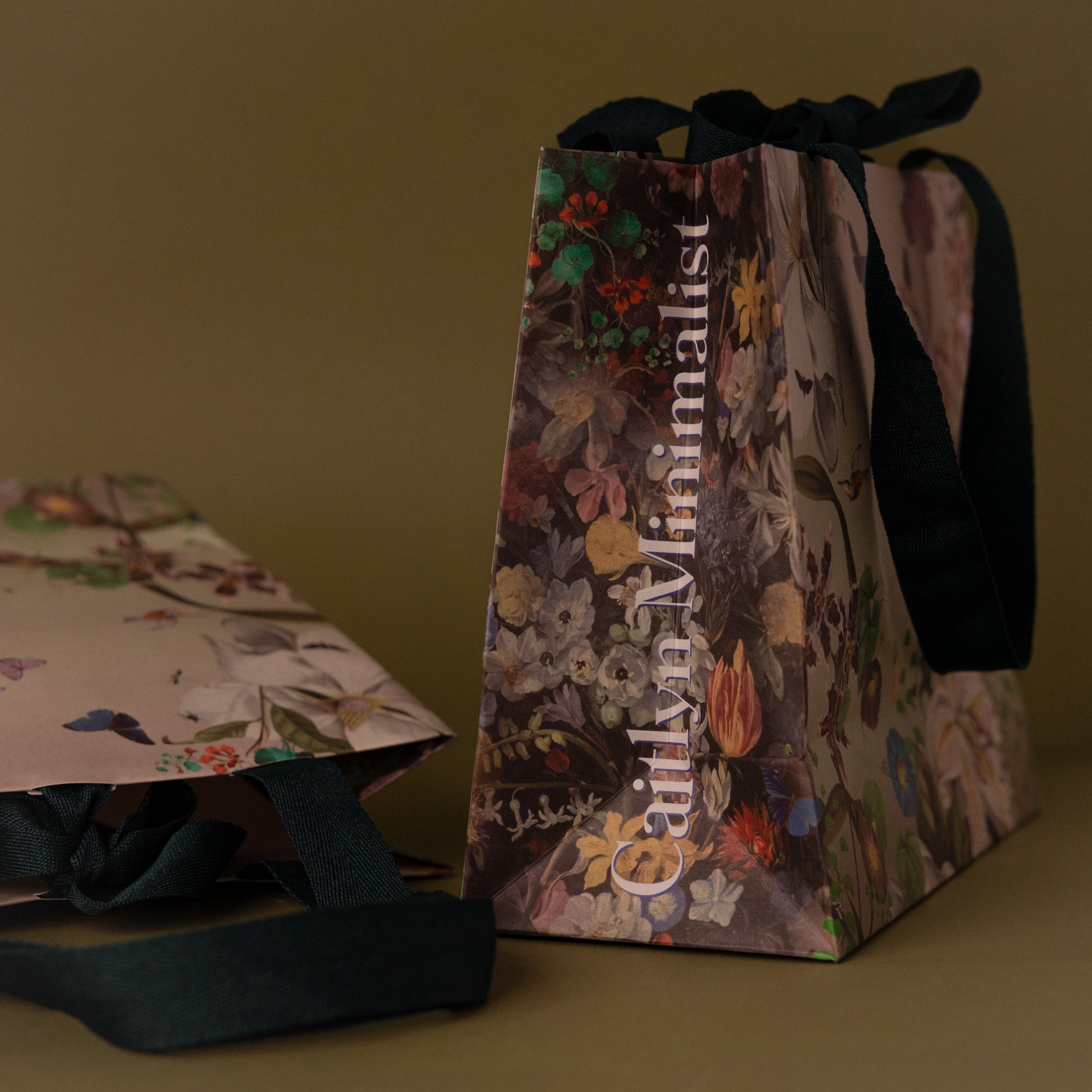 The Floral Gift Bag Add-On features floral patterns, black handles, and Cultivated Minimalist text, adding an elegant finishing touch to your gift wrapping.