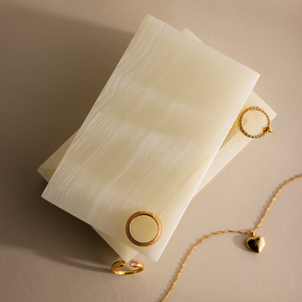 Green Onyx Jewelry Box: A rectangular green onyx jewelry box with gold circular clasps, shown next to a gold chain and ring on a beige background.