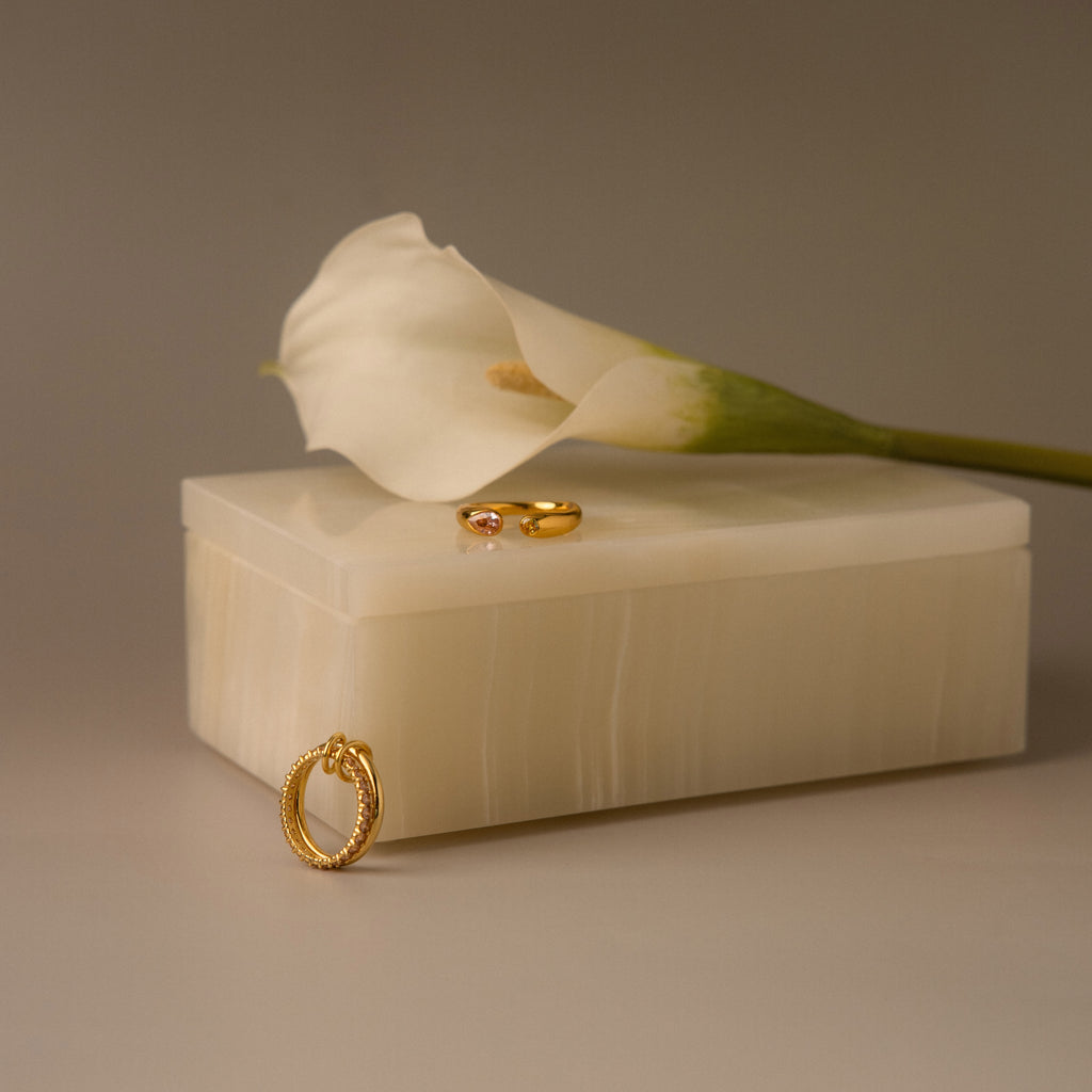 A white calla lily, gold rings, and a gold earring rest on a handcrafted Green Onyx Jewelry Box, set against a neutral background.