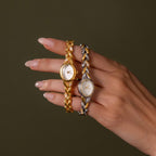 Hand holding two elegant womens watches: a gold-tone watch and the Chevron Diamond Link Timepiece, displayed against a plain background.