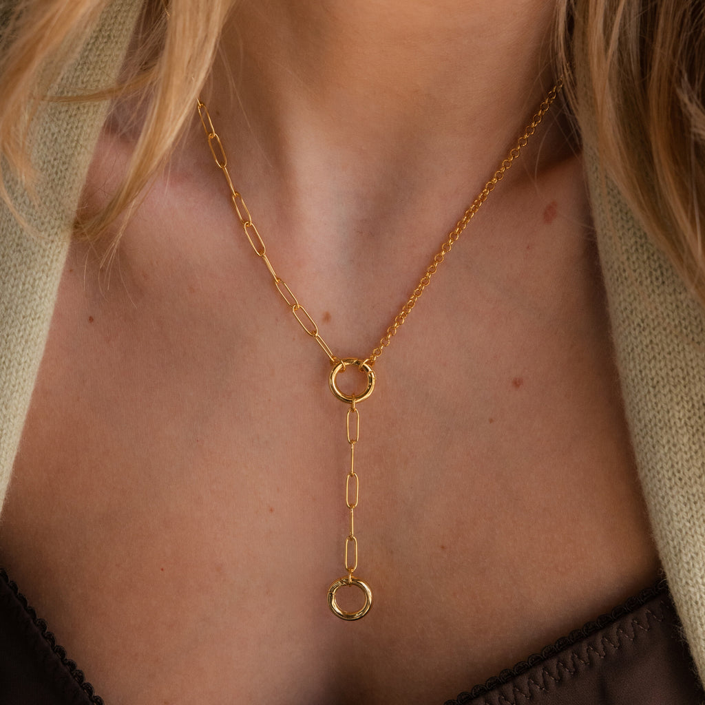 A Rolo Lariat Paperclip Clasp Necklace featuring two circular pendants is elegantly worn around a woman's neck.