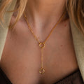A Rolo Lariat Paperclip Clasp Necklace featuring two circular pendants is elegantly worn around a woman's neck.