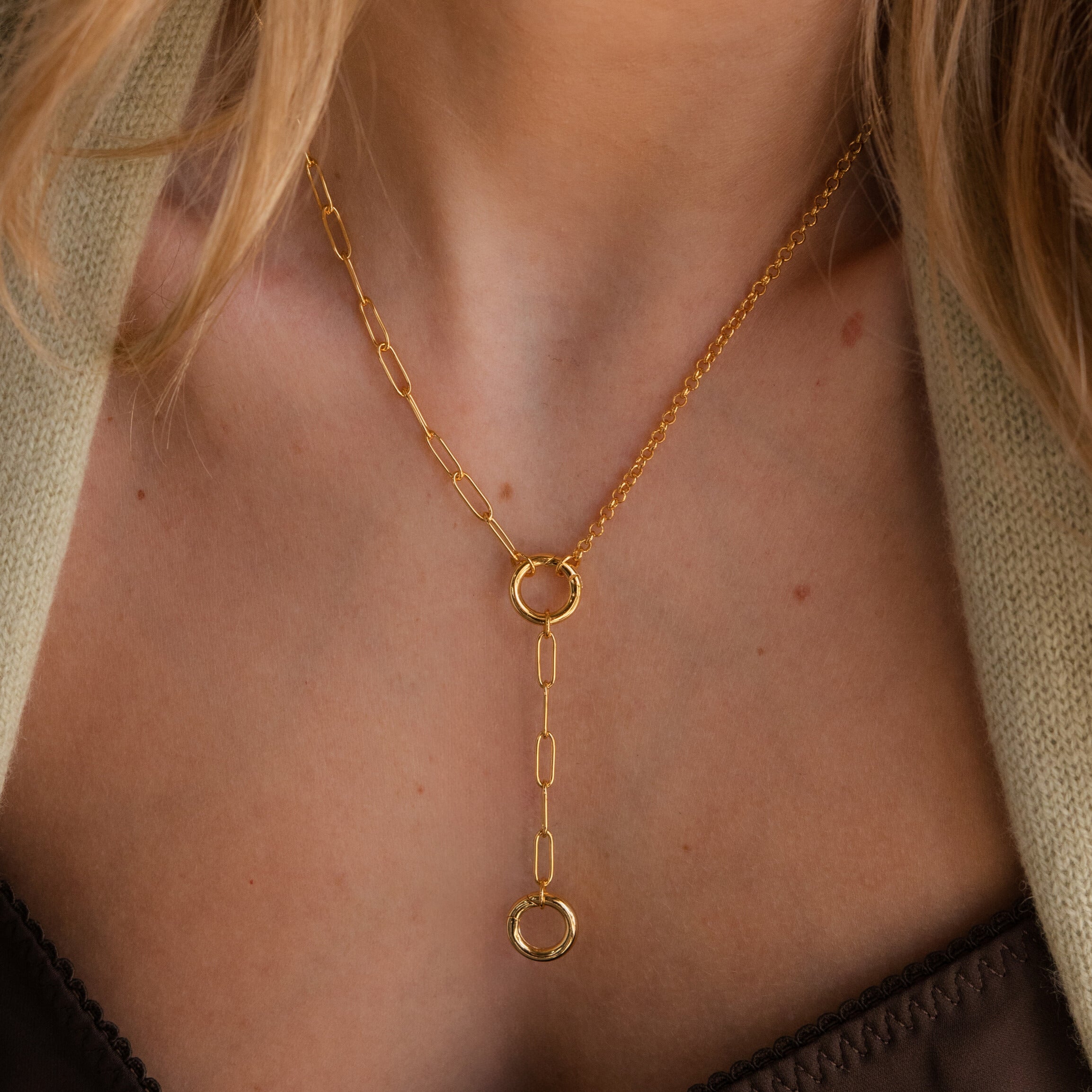A Rolo Lariat Paperclip Clasp Necklace featuring two circular pendants is elegantly worn around a woman's neck.