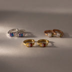 The Multiple Baguette Birthstone Huggies in silver, gold, and rose gold are displayed on a neutral surface—ideal for mixing with colorful jewelry or stacking beside your favorite petite hoops.