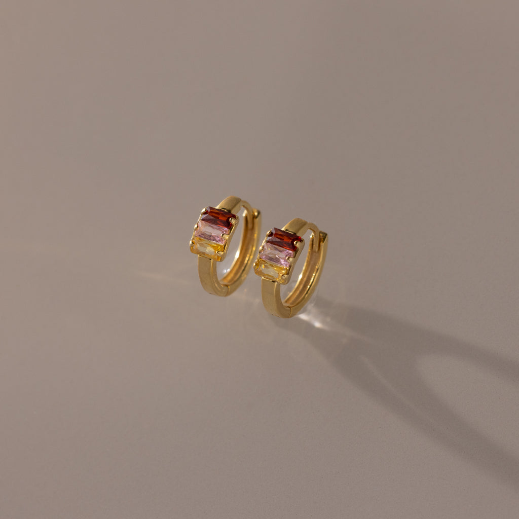 Multiple Baguette Birthstone Huggies in 18K Gold shown on a neutral background, perfect for adding a pop of colorful elegance to any outfit.