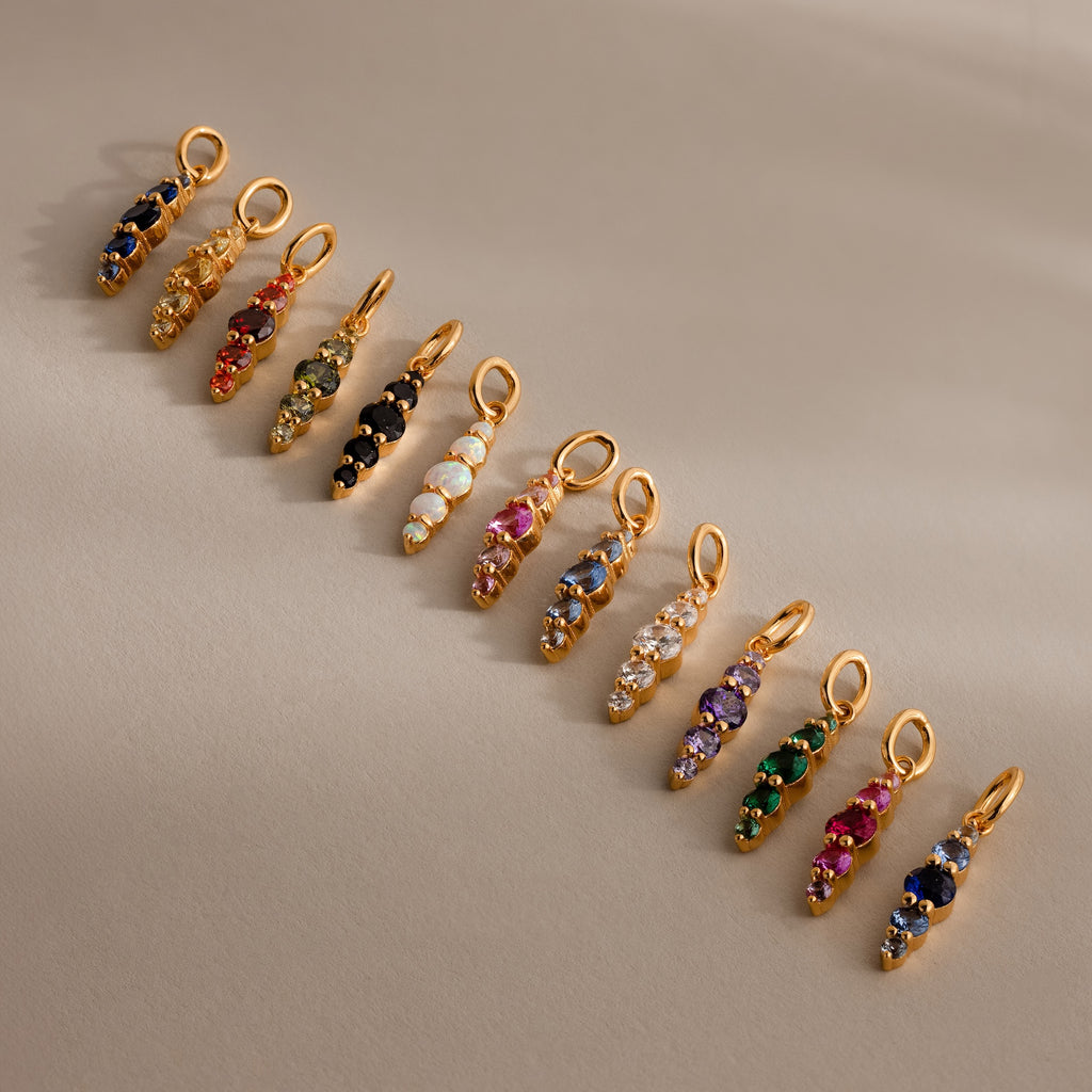 Twelve Ombre Lace Alexandrite Charms, each with a unique colored gemstone, form a radiant personalized row inspired by the Ombre Lace Birthstone Charm collection.