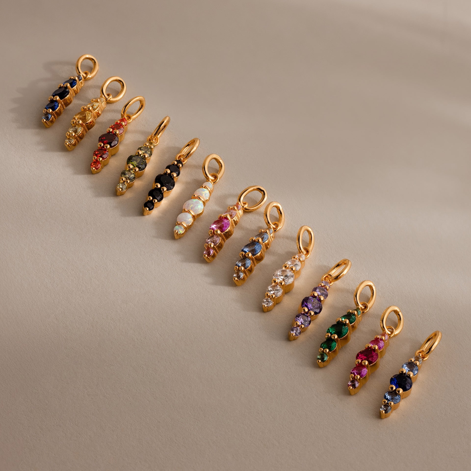 Twelve Ombre Lace Alexandrite Charms, each with a unique colored gemstone, form a radiant personalized row inspired by the Ombre Lace Birthstone Charm collection.