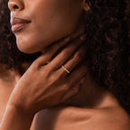 Close-up of a woman touching her neck, wearing a Dainty Ribbed Ruby Ring on her finger.