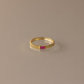 The Dainty Ribbed Ruby Ring features a gold ribbed band with a small rectangular pink gemstone at the center, ideal as a birthstone ring or for stacking.