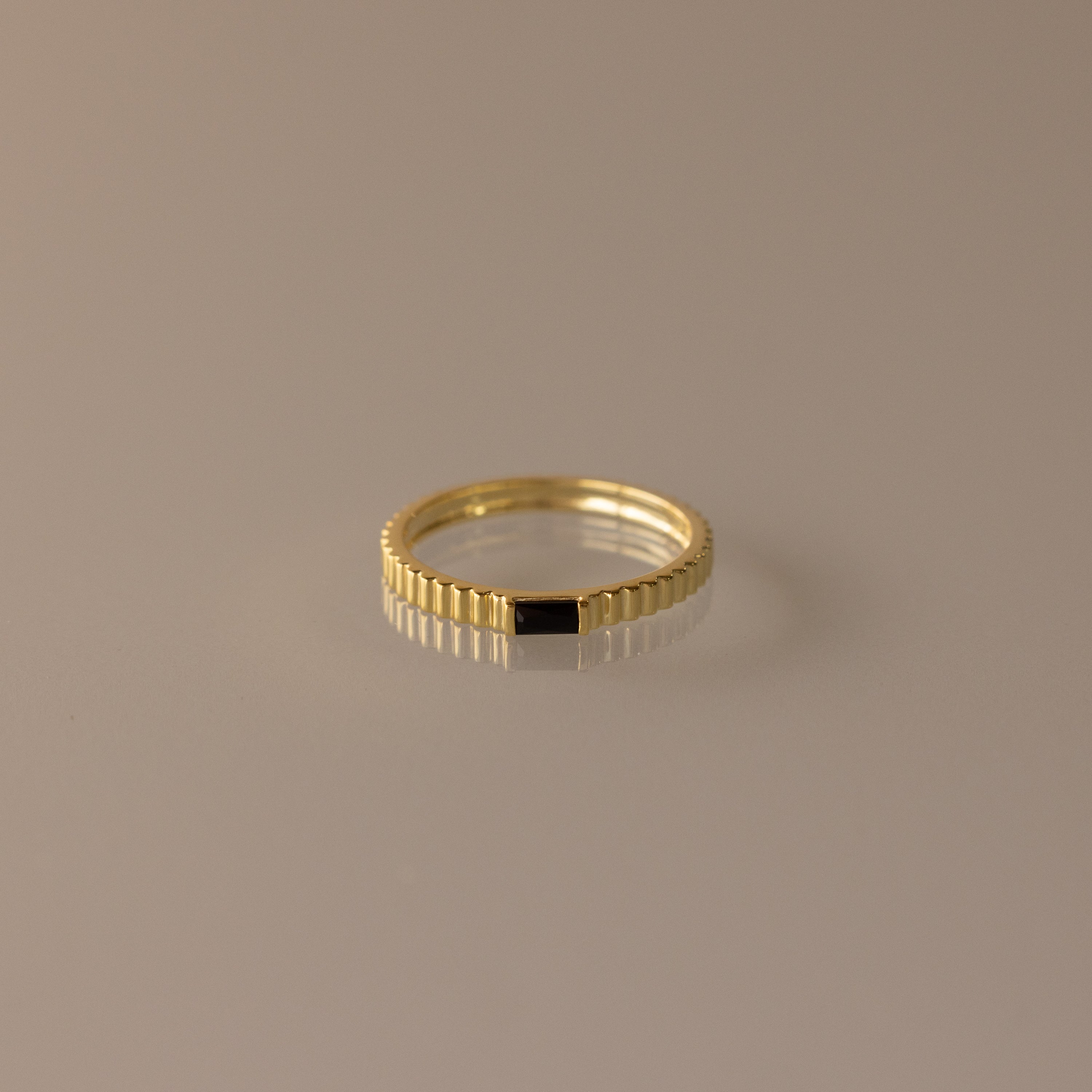 The Dainty Ribbed Onyx Ring features a thin gold band with a subtle ridged design and a small black rectangular onyx detail, shown against a neutral background.