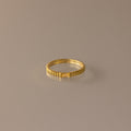 The Dainty Ribbed Topaz Ring, featuring a delicate ridged design in gold, is elegantly showcased on a neutral beige background.