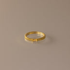 The Dainty Ribbed Topaz Ring, featuring a delicate ridged design in gold, is elegantly showcased on a neutral beige background.